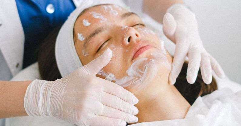 Natural Skincare - From above of crop faceless cosmetician applying facial mask on customer face during cosmetic procedure in modern spa salon
